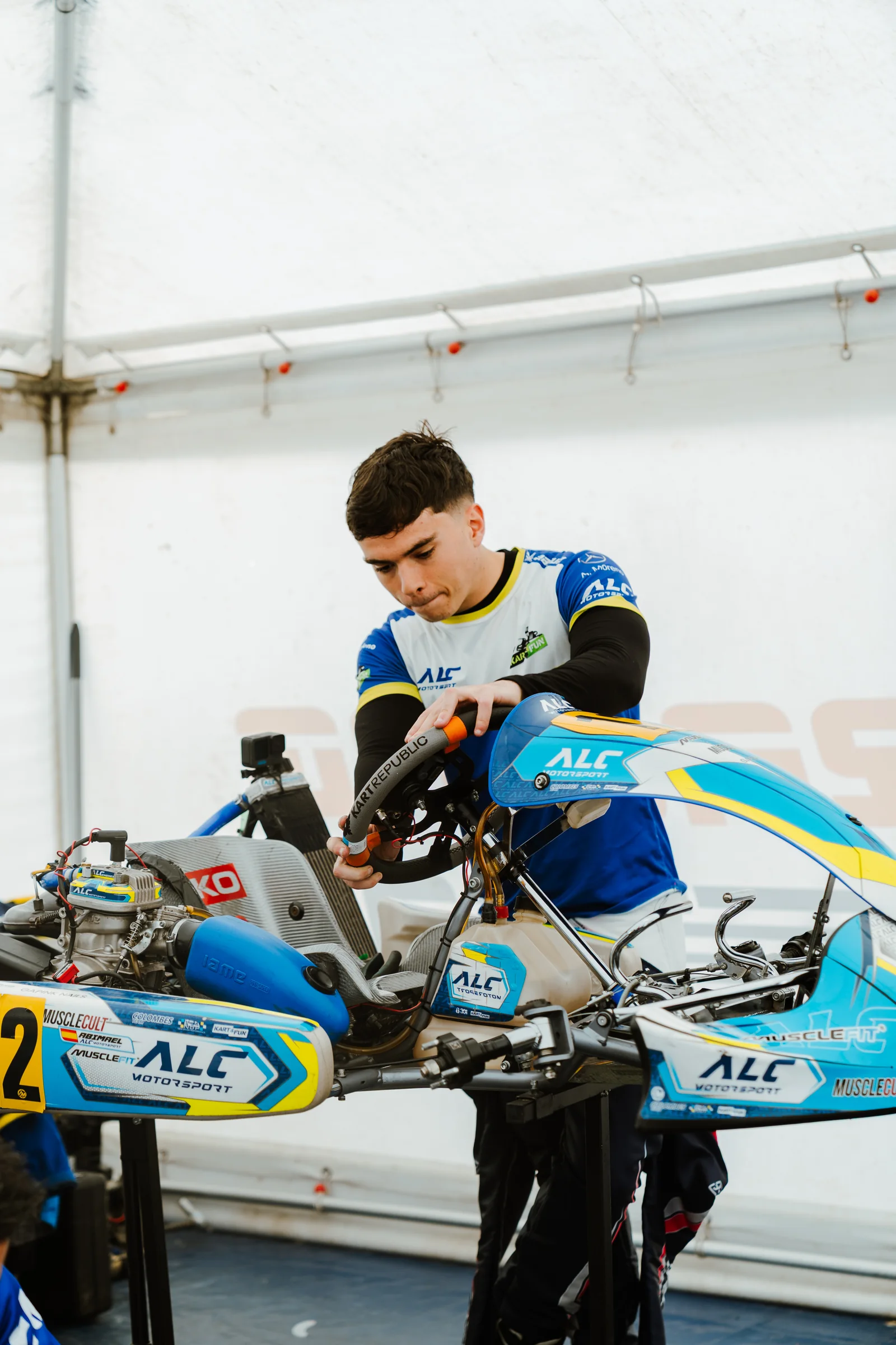 Miembro de ALC Motorsport trabajando sobre un kart del equipo dentro de la carpa